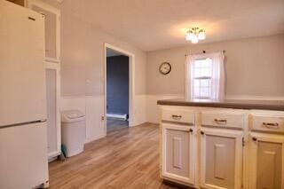 kitchen with white refrigerator, white cabinetry, and light wood-type flooring