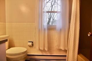 bathroom featuring toilet, tile walls, and a baseboard heating unit