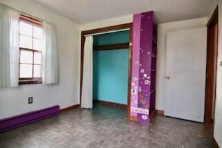 unfurnished bedroom featuring a closet and a baseboard heating unit