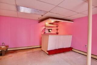 basement featuring a baseboard radiator, indoor bar, and a paneled ceiling