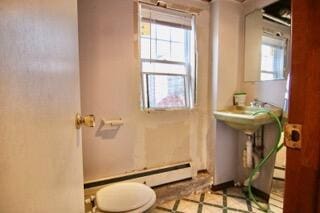 bathroom with a wealth of natural light, toilet, and baseboard heating