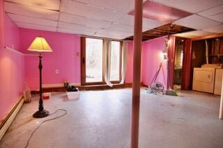 basement featuring baseboard heating, washer and clothes dryer, and a drop ceiling