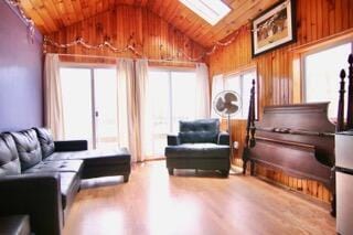 interior space with wooden walls, lofted ceiling with skylight, hardwood / wood-style floors, and wooden ceiling