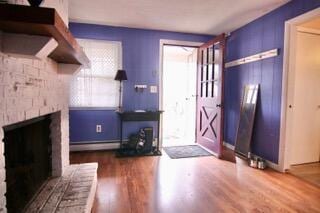 entrance foyer with wood-type flooring, a fireplace, and baseboard heating