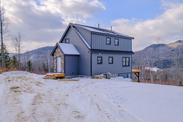 snow covered rear of property featuring a mountain view