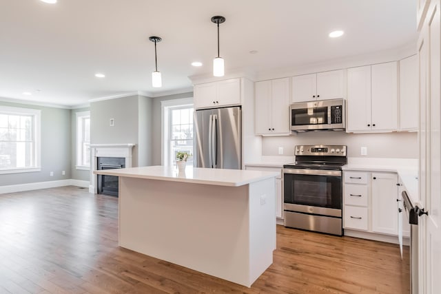 kitchen featuring hanging light fixtures, light hardwood / wood-style flooring, stainless steel appliances, and white cabinets