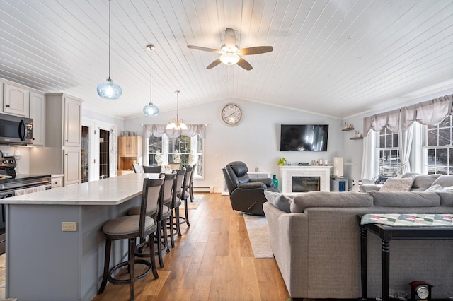 living room featuring lofted ceiling, wood ceiling, crown molding, light wood-type flooring, and ceiling fan with notable chandelier