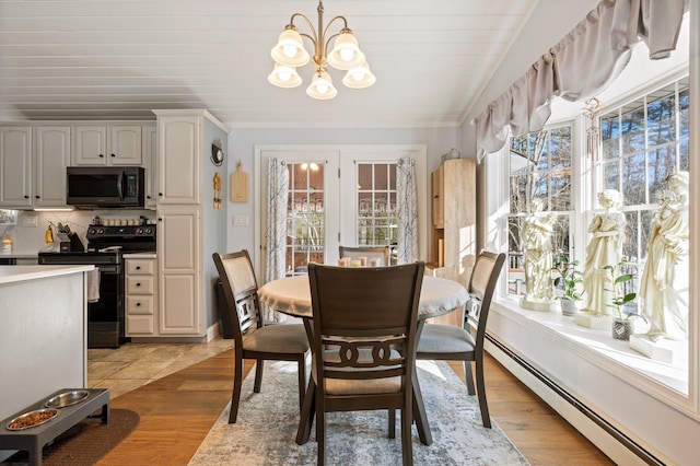 dining area with an inviting chandelier, light wood-type flooring, vaulted ceiling, and baseboard heating