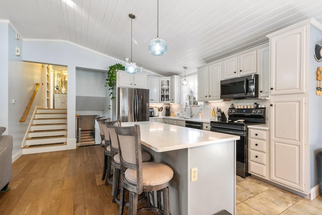 kitchen featuring hanging light fixtures, a kitchen breakfast bar, a kitchen island, stainless steel appliances, and white cabinets