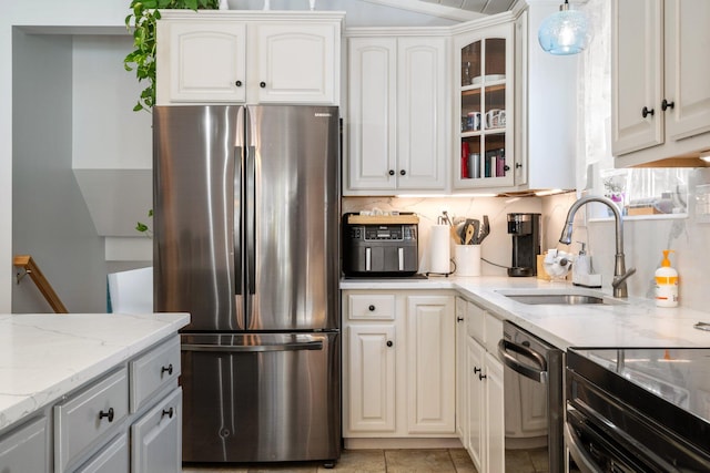 kitchen with sink, white cabinetry, backsplash, stainless steel appliances, and light stone counters