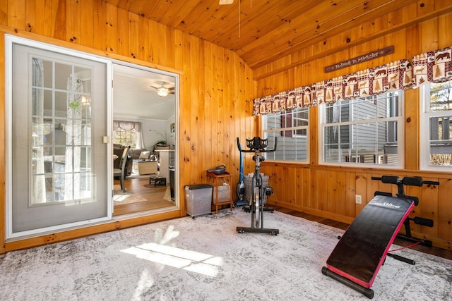 exercise room featuring vaulted ceiling, wooden ceiling, ceiling fan, and wood walls