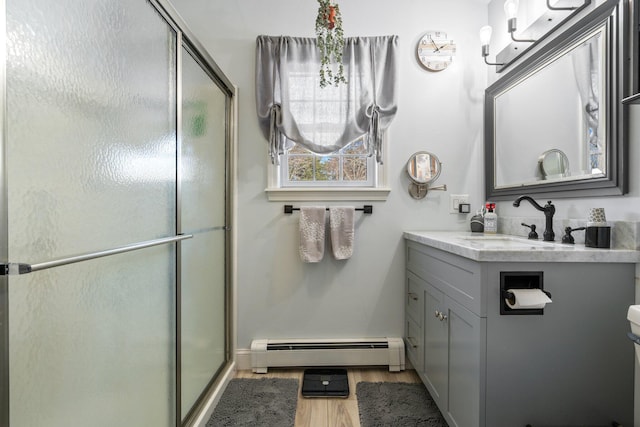 bathroom featuring hardwood / wood-style flooring, a baseboard radiator, vanity, and an enclosed shower