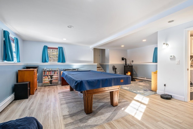 playroom featuring light hardwood / wood-style flooring, billiards, baseboard heating, and a wood stove