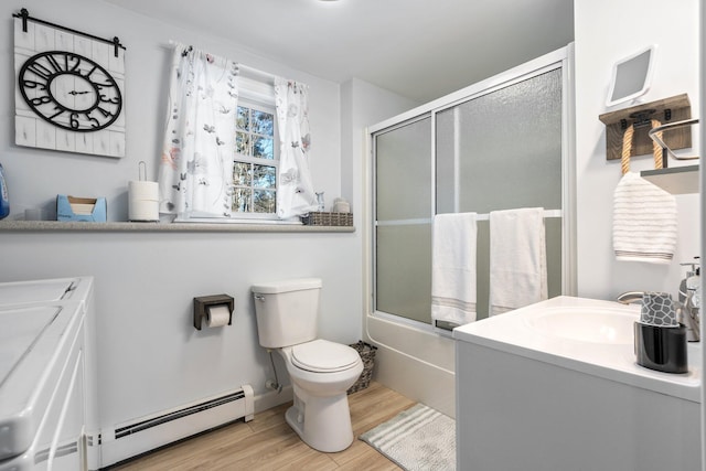 full bathroom with washing machine and clothes dryer, toilet, wood-type flooring, bath / shower combo with glass door, and a baseboard radiator