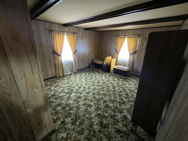 sitting room featuring dark carpet, wooden walls, and beamed ceiling