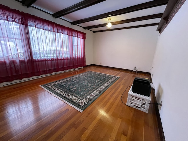 unfurnished room with hardwood / wood-style floors and beamed ceiling