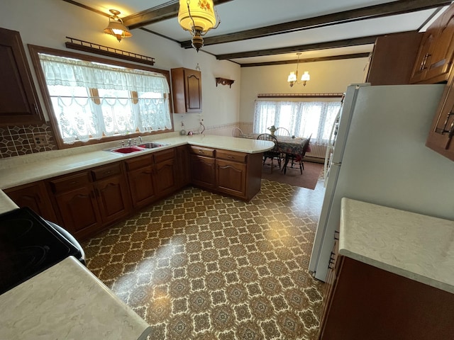 kitchen with pendant lighting, sink, kitchen peninsula, beamed ceiling, and white fridge