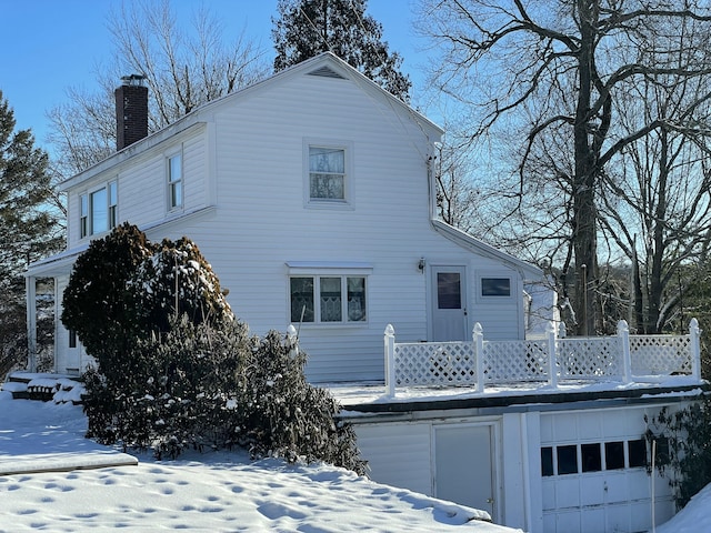 snow covered back of property with a garage