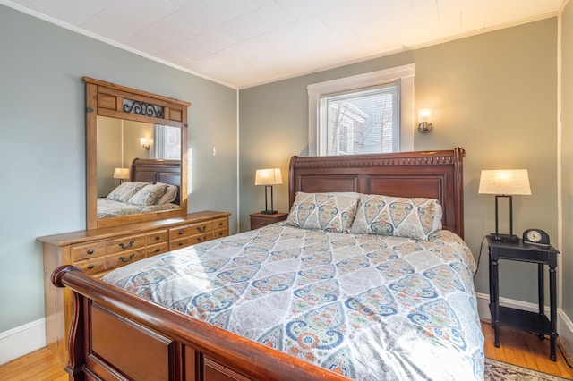 bedroom featuring crown molding and light hardwood / wood-style flooring