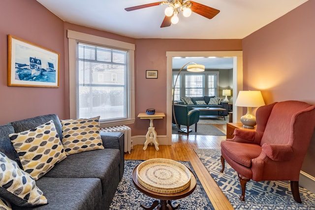 living room with hardwood / wood-style floors, radiator, and ceiling fan