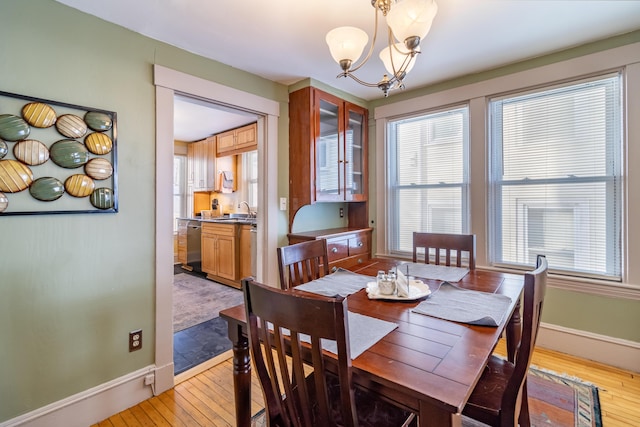 dining area with sink, light hardwood / wood-style floors, and a chandelier