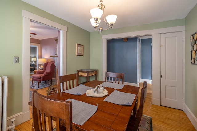 dining area with a notable chandelier, light hardwood / wood-style flooring, and radiator