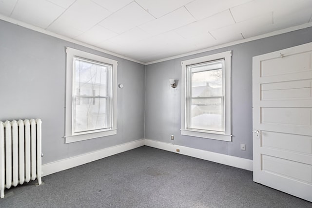 carpeted spare room with radiator and crown molding