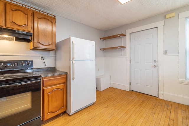 kitchen featuring black / electric stove, light hardwood / wood-style flooring, a textured ceiling, and white refrigerator