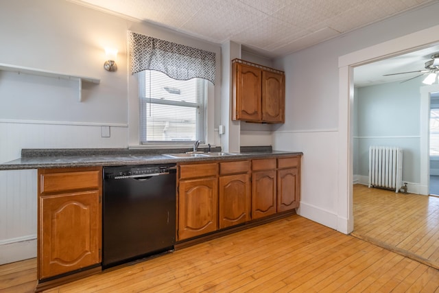 kitchen with radiator, sink, light hardwood / wood-style flooring, ceiling fan, and black dishwasher