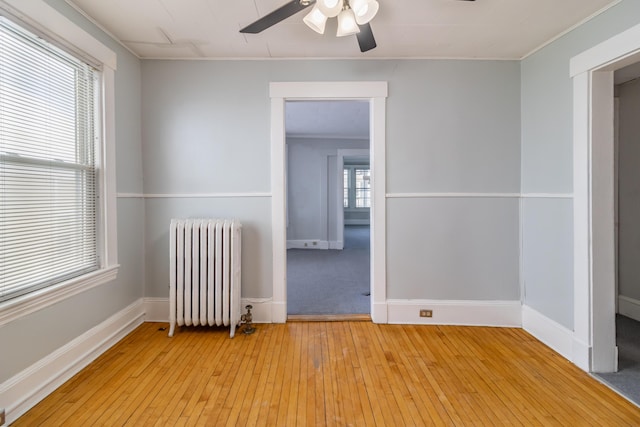 spare room featuring crown molding, ceiling fan, radiator, and light hardwood / wood-style flooring