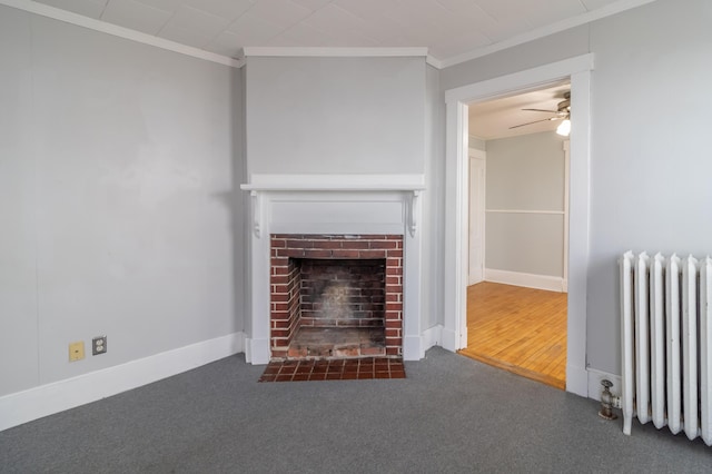 unfurnished living room featuring dark colored carpet, ornamental molding, radiator, ceiling fan, and a fireplace