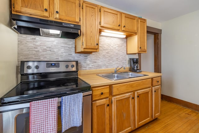 kitchen featuring light hardwood / wood-style flooring, sink, stainless steel range with electric cooktop, and backsplash