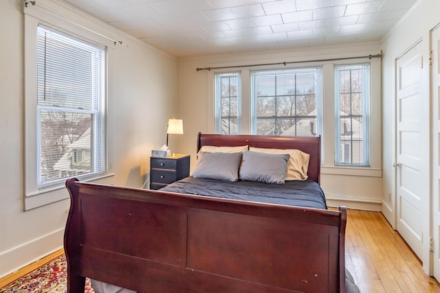 bedroom with crown molding and light wood-type flooring