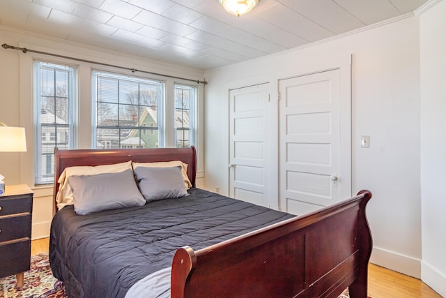 bedroom featuring ornamental molding and light wood-type flooring