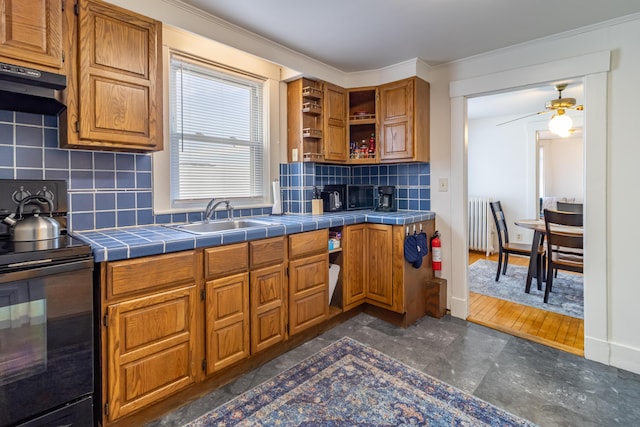 kitchen with sink, black / electric stove, radiator heating unit, tile counters, and decorative backsplash