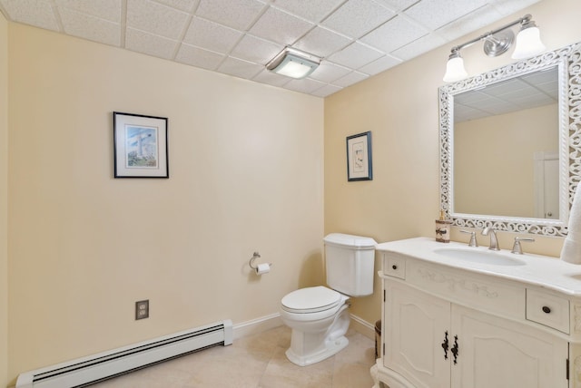 bathroom featuring tile patterned flooring, vanity, a drop ceiling, a baseboard radiator, and toilet