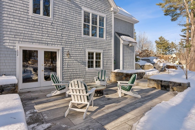 snow covered deck featuring a patio and french doors