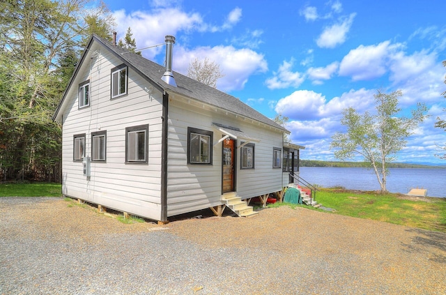 view of front of home with entry steps, a shingled roof, and a water view