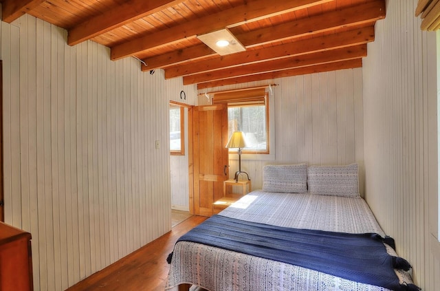 bedroom with wood ceiling, wood walls, light wood-style flooring, and beam ceiling