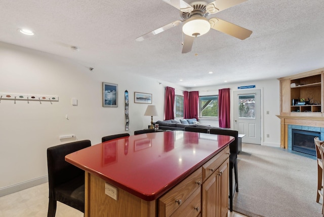 kitchen featuring light colored carpet, a fireplace, a kitchen island, and a textured ceiling