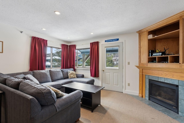 living room with a tile fireplace, light colored carpet, and a textured ceiling