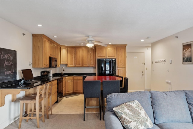 kitchen featuring sink, a breakfast bar, ceiling fan, black appliances, and light colored carpet