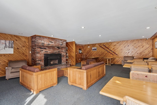 living room featuring dark colored carpet, a brick fireplace, and wooden walls