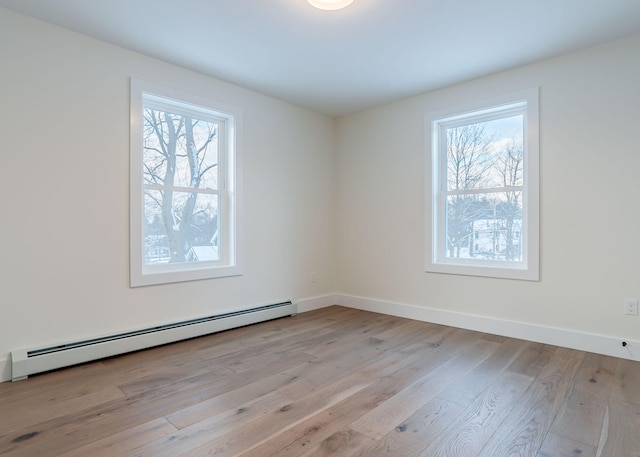 spare room with a wealth of natural light, a baseboard radiator, and light hardwood / wood-style floors