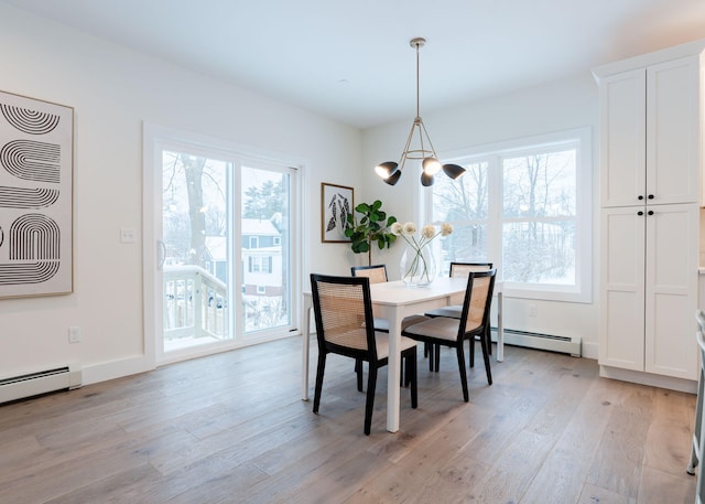 dining space with a baseboard radiator, a notable chandelier, and light wood-type flooring