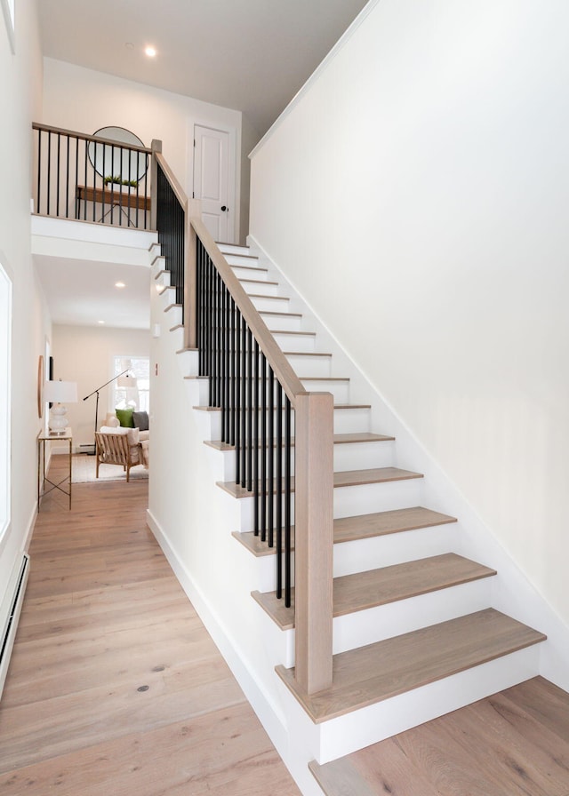 staircase with hardwood / wood-style floors and a high ceiling