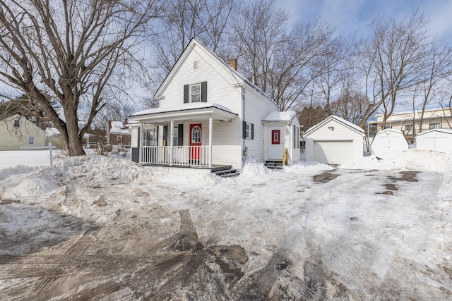 view of front facade featuring a porch, an outbuilding, a detached garage, and a chimney