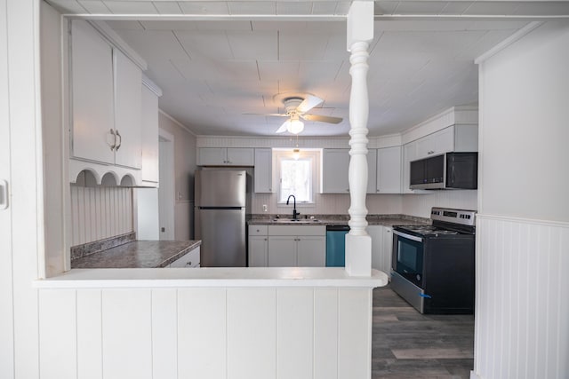 kitchen featuring stainless steel appliances, a peninsula, a sink, and white cabinetry