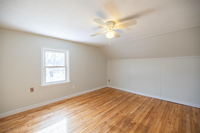 additional living space featuring vaulted ceiling, light wood-type flooring, a ceiling fan, and baseboards