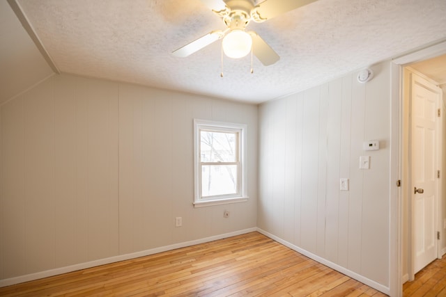 empty room featuring light wood finished floors, ceiling fan, baseboards, and a textured ceiling